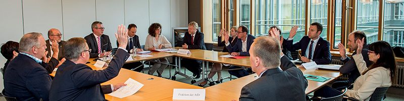 Die Abgeordneten arbeiten in einer kleinen Gruppen um den Tisch im Besprechungsraum