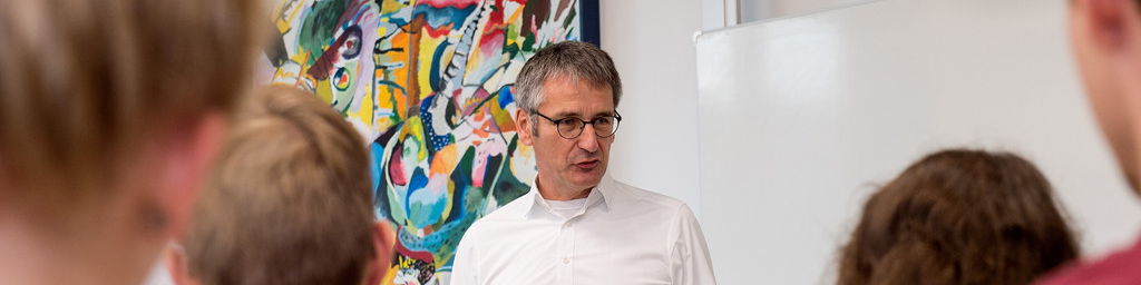 Landtagspräsident Hendrik Hering spricht vor einer Schulklasse. 